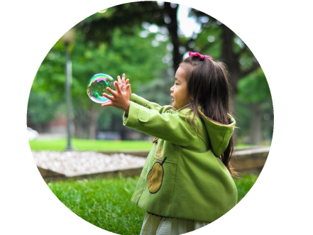 Niña jugando libremente con pompa de jabón. Muy Montessori.