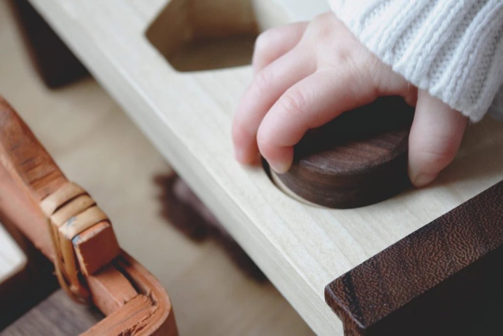 Colegios Montessori: niño jugando en escuela infantil con material de resaques de madera.